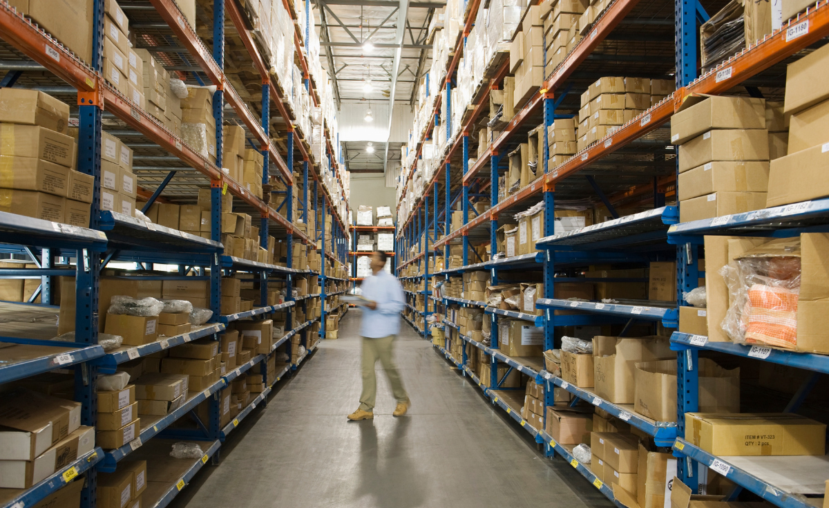 A worker checking inventory in a large warehouse